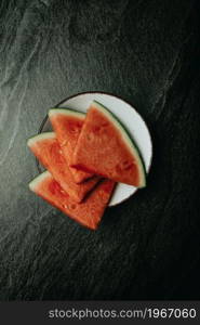 Aerial image of a bowl filled with watermelon over a black marble table, fresh food, wellness, healthy food