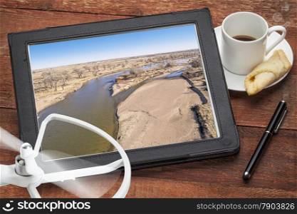 aerial landscape photography concept - reviewing aerial pictures of the South Platte RIver in Colorado on a digital tablet with a drone rotor and cup of coffee, screen picture copyright by the photographer