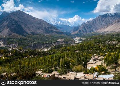 Aerial landscape view of green Hunza Nagar valley in October, separated by river and surrounded by Karakoram mountain range. Gilgit Baltistan, Pakistan.