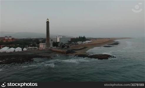 Aerial - Maspalomas Lighthouse and resort area with people on the coast of Gran Canaria. Evening scene