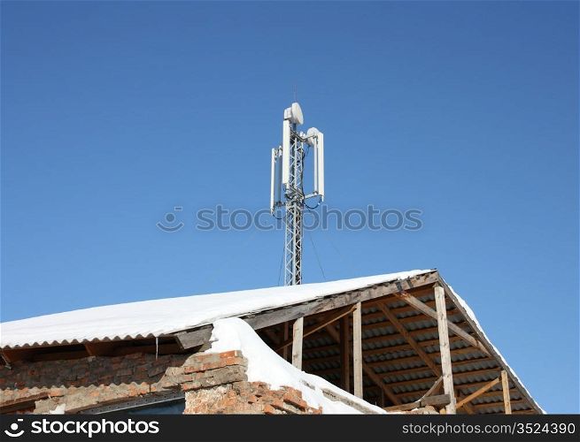 Aerial mobile communication on a roof of the old house against the blue sky