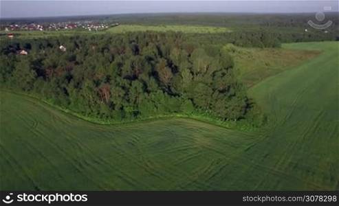 Aerial nature scene with green woods, fields and village in the distance. Russian summer landscapes