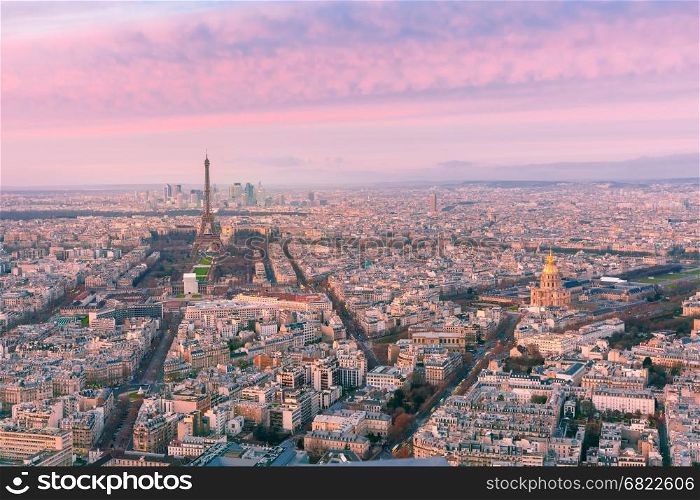 Aerial night view of Paris, France. Aerial panoramic view of Paris skyline with Eiffel Tower, Les Invalides and business district of Defense at pink sunset, as seen from Montparnasse Tower, Paris, France