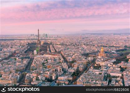 Aerial night view of Paris, France. Aerial panoramic view of Paris skyline with Eiffel Tower, Les Invalides and business district of Defense at pink sunset, as seen from Montparnasse Tower, Paris, France