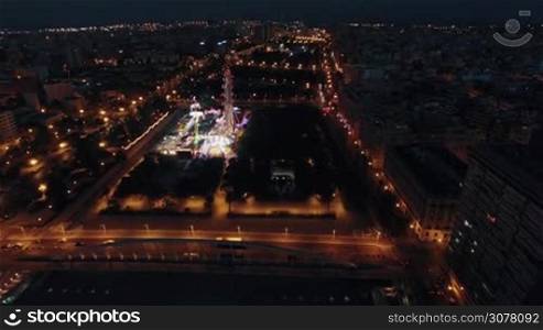 Aerial - Night view of Valencia with illuminated fun fair in the park, Spain