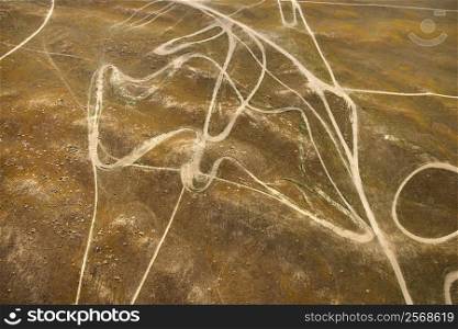 Aerial of barren landscape with dirt road trails in California, USA.