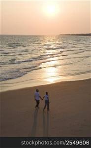 Aerial of couple holding hands and walking on beach on Bald Head Island, North Carolina.