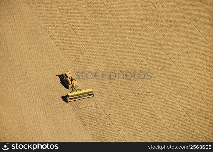 Aerial of farmer tilling crop field in farmland, USA.