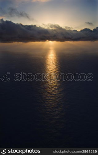 Aerial of sun setting over Pacific ocean with clouds.
