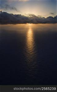 Aerial of sun setting over Pacific ocean with clouds.