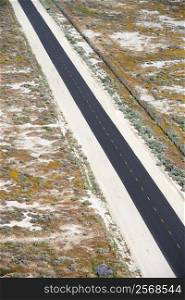 Aerial of two lane highway through desolate landscape.