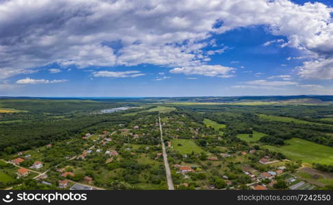 Aerial panorama from a drone of countryside, village, green fields and trees, agriculture concept. Countryside farmland