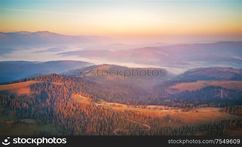 Aerial panorama of beautiful autumn mountains. Sunrise over mountain foggy valley. Misty woodland in the morning. Carpathians, Ukraine