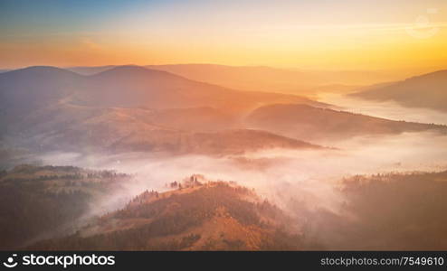 Aerial panorama of beautiful autumn mountains. Sunrise over mountain foggy valley. Misty woodland in the morning. Carpathians, Ukraine