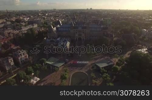 Aerial panorama of Dutch capital with view to Rijksmuseum, Art Square with pond and I amsterdam slogan. Cityscape at sunset