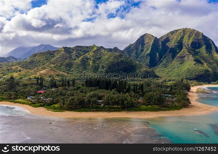 Aerial panoramic image off the coast over Tunnels beach on Hawaiian island of Kauai with Na Pali mountains behind. Aerial drone shot of Tunnels Beach on the north shore of Kauai in Hawaii