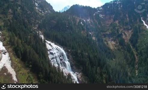 Aerial panoramic view of a waterfall on the pine forest and with sunlights in the mountains in Austria