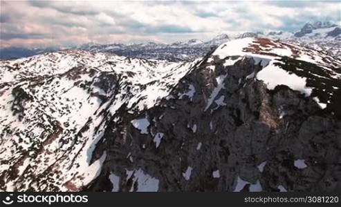 Aerial panoramic view of snowy mountains with rocks in sunset. On the horizon many mountains where skiing. Obertraun, Austria