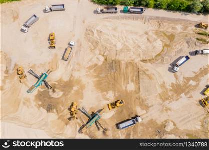 Aerial photo of excavator pours sand into the truck. On the construction site top view. Shooting from the drone.
