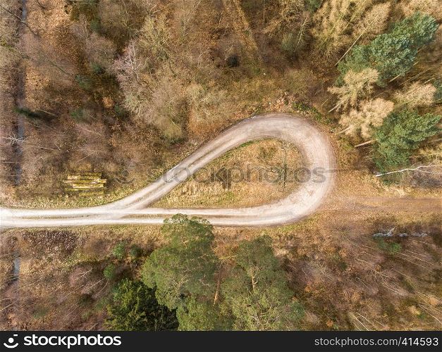 Aerial photograph taken vertically from a turning loop in a forest ridge with large spruce, pine and fir trees, abstract aerial view, drone shot