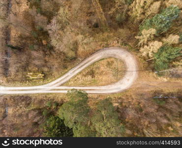 Aerial photograph taken vertically from a turning loop in a forest ridge with large spruce, pine and fir trees, abstract aerial view, drone shot