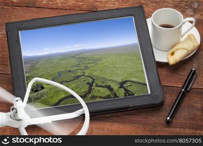 aerial photography concept - reviewing aerial pictures of the Illinois River (North Park, Colorado) on a digital tablet with a drone rotor and coffee, screen picture copyright by the photographer