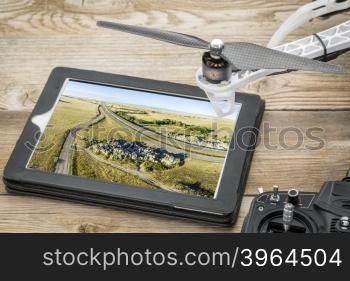 Aerial photography concept - reviewing picture of Natural Fort, highway and prairie on a digital tablet with a drone and radio controller