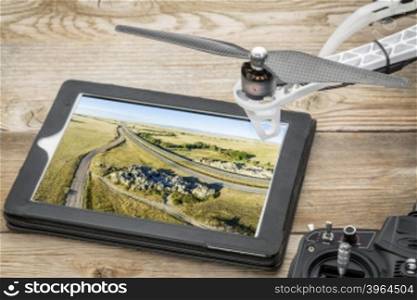 Aerial photography concept - reviewing picture of Natural Fort, highway and prairie on a digital tablet with a drone and radio controller