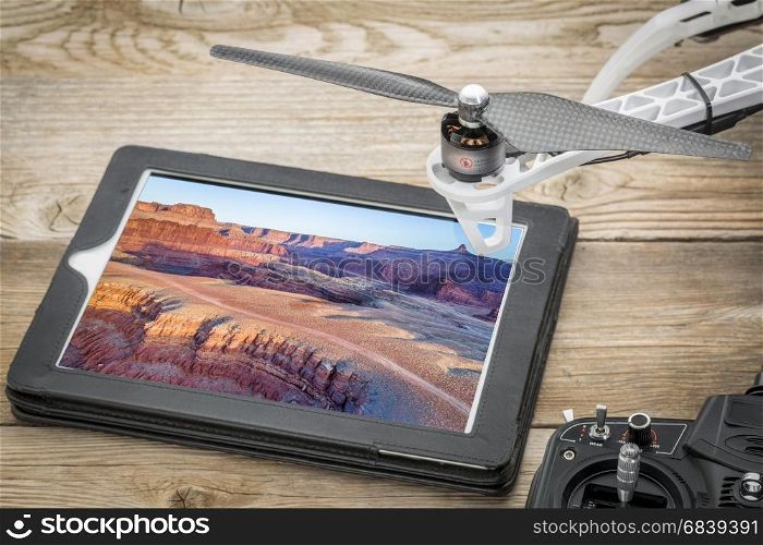 aerial photography concept - reviewing pictures of Colorado River canyon near Moab, Utah, on a digital tablet with a drone rotor and radio controller, screen picture copyright by the photographer