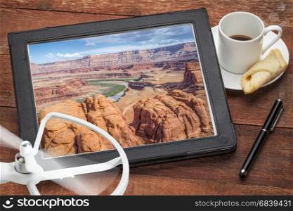 aerial photography concept - reviewing pictures of Colorado River canyon near Moab, Utah, on a digital tablet with a drone rotor and coffee, screen picture copyright by the photographer
