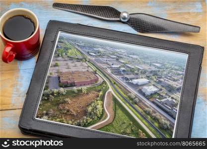 aerial photography concept - reviewing pictures of Fort Collins city on a digital tablet with a cup of coffee