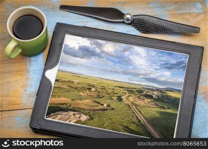 aerial photography concept - reviewing pictures of prairie landscape on a digital tablet with a cup of coffee