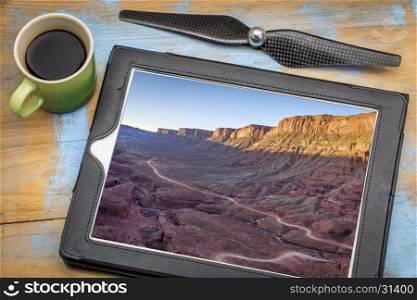 aerial photography concept - reviewing pictures of Utah canyon landscape on a digital tablet with a cup of coffee