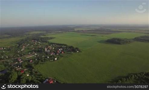 Aerial rural scene. View with village, vast green fields and woods. Russian countryside