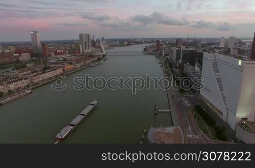 Aerial scene of Rotterdam with Erasmus Bridge, city buildings and ship sailing along the river. View in the evening, Netherlands