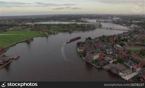 Aerial scene with Dutch township, green fields and ship sailing along the river
