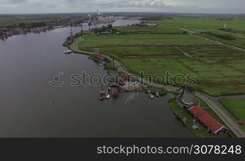 Aerial shot of Dutch village with view to the river, old windmills and green fields