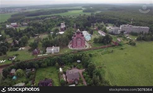 Aerial shot of green forested areas of Lukino Village with Cathedral of Ascension, Russia