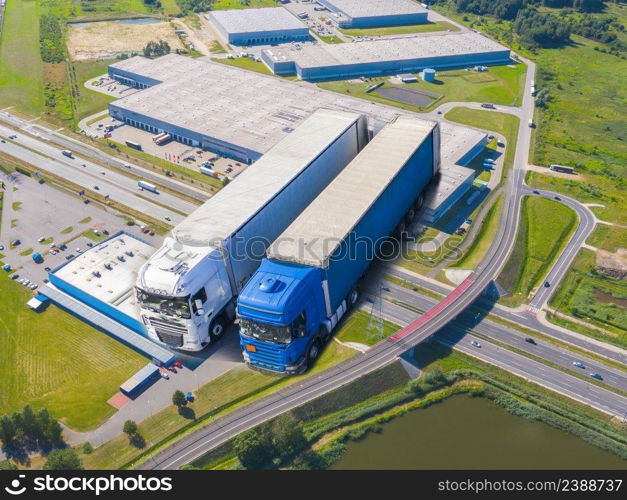 Aerial Shot of Industrial Warehouse Loading Dock where Many Truck with Semi Trailers Load Merchandise.