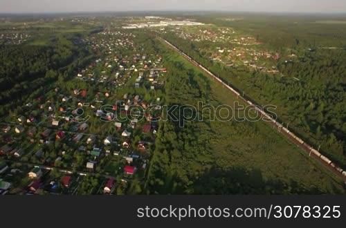 Aerial shot of Russian countryside with village, green woods and trains running there
