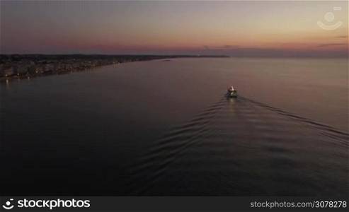 Aerial shot of sailing boat and coastline with hotels alongside at night. Thessaloniki Greece