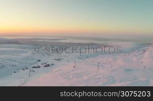Aerial shot of sunrise in Khibiny mountains in Russia, there is a ski resort at the bottom