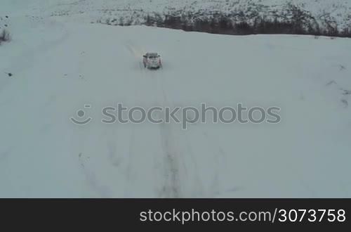 Aerial shot of the driving on winter snowy road in the countryside, back view