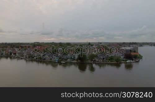 Aerial shot of village houses on the riverside, Netherlands. Scenic waterfront view
