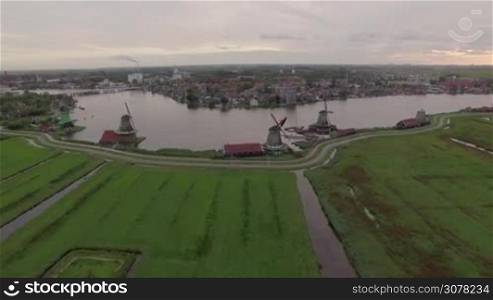 Aerial shot of village near Amsterdam with old windmills and green fields, Netherlands