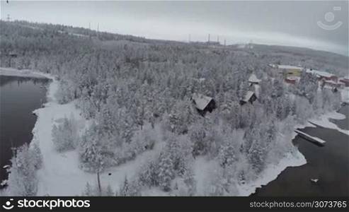 Aerial shot of winter camp located in pine wood in Finland. Snowy landscape with lakes