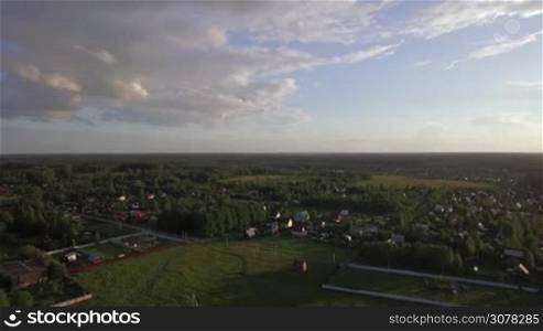 Aerial summer scene of village with private houses among the green woods and fields, Russia