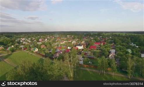 Aerial summer scene with village near the highway, green woods and fields, Russia