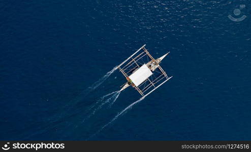 Aerial top down view of boat moving in open sea with clear and turquoise water on over coral reef, Boat left the tropical lagoon, Moalboal, Oslob, Cebu Island, Philippines.