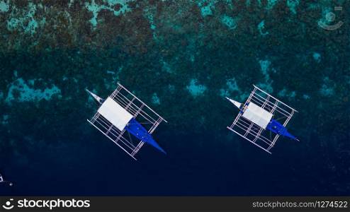 Aerial top down view of boat moving in open sea with clear and turquoise water on over coral reef, Boat left the tropical lagoon, Moalboal, Oslob, Cebu Island, Philippines.